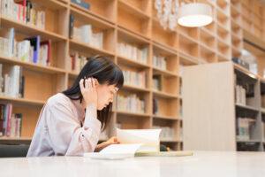 female college student reading a book at the library